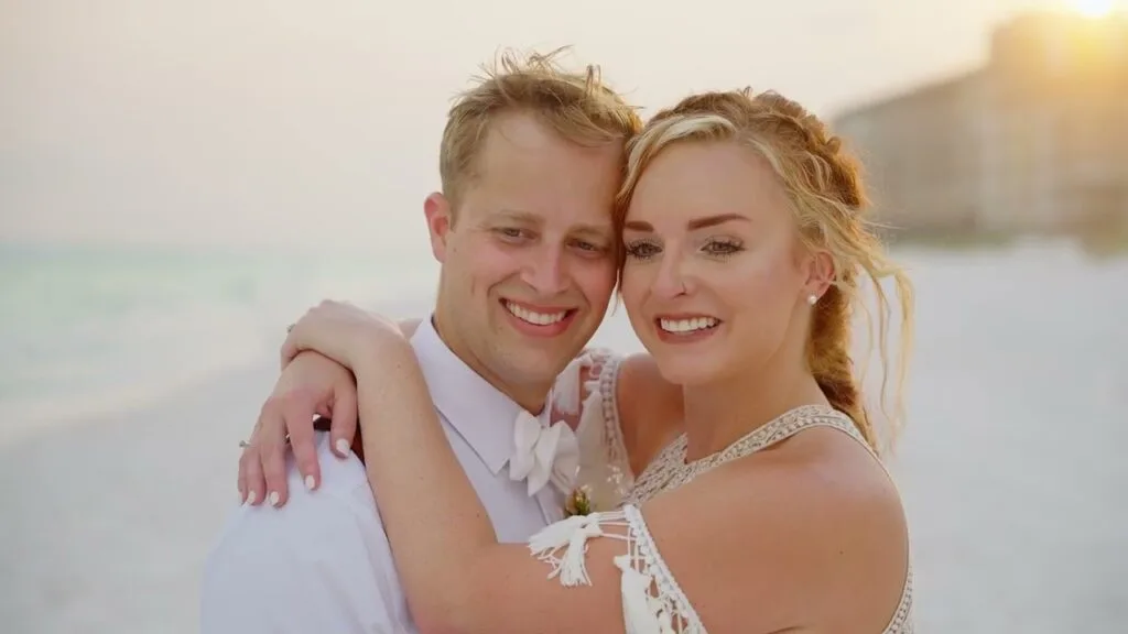 Destin Wedding Venues: Beach, Harbor and Bay (2027 Guide) 1 Kevin and Josie holding each other on the beach in warm sunset light, a still from their destination wedding film