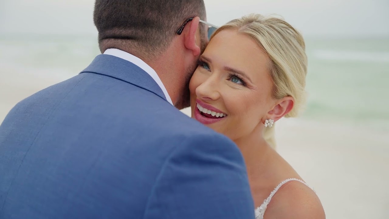 Pensacola Wedding Videographer 7 Ashley smiling over Ryan's shoulder as he holds her on the beach, from their Pensacola Beach wedding film