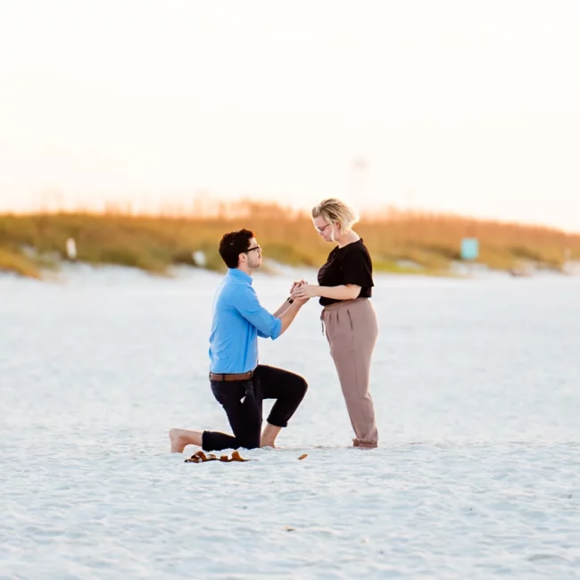 a man and woman standing on a beach holding hands