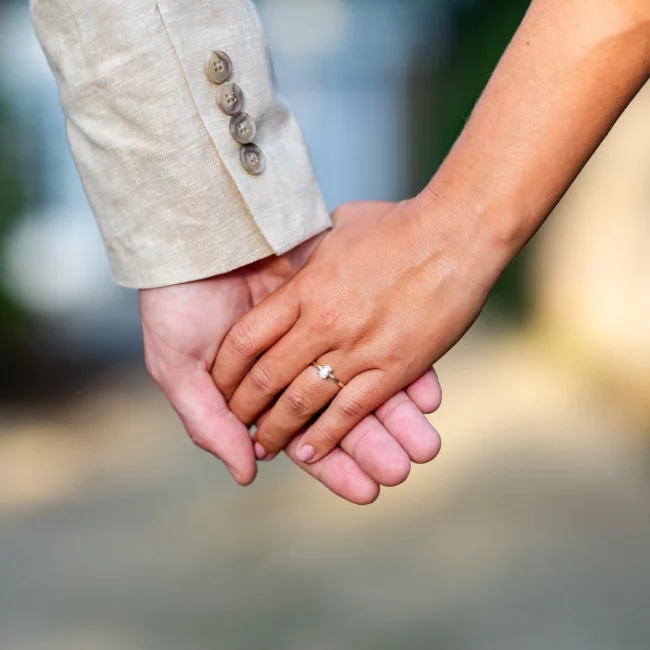 a close up of a couple holding hands with a woman wearing a new engagement ring - Engagement Shoot in Mobile, AL at springhill college by KDH Weddings