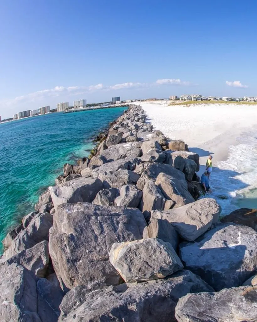Destin Wedding Venues: Beach, Harbor and Bay (2027 Guide) 3 The Destin jetties - a long line of grey granite boulders running out between turquoise Gulf water and white sand, with the town beyond