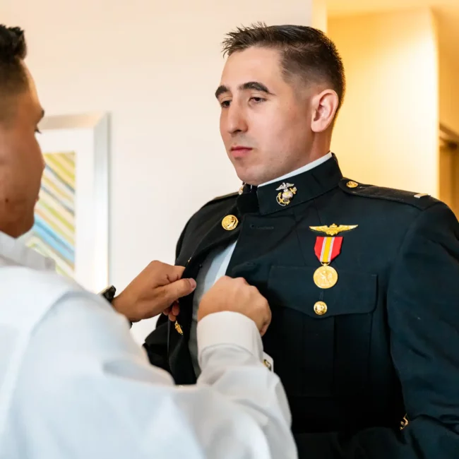 man helping groom in usmc dress blues before wedding