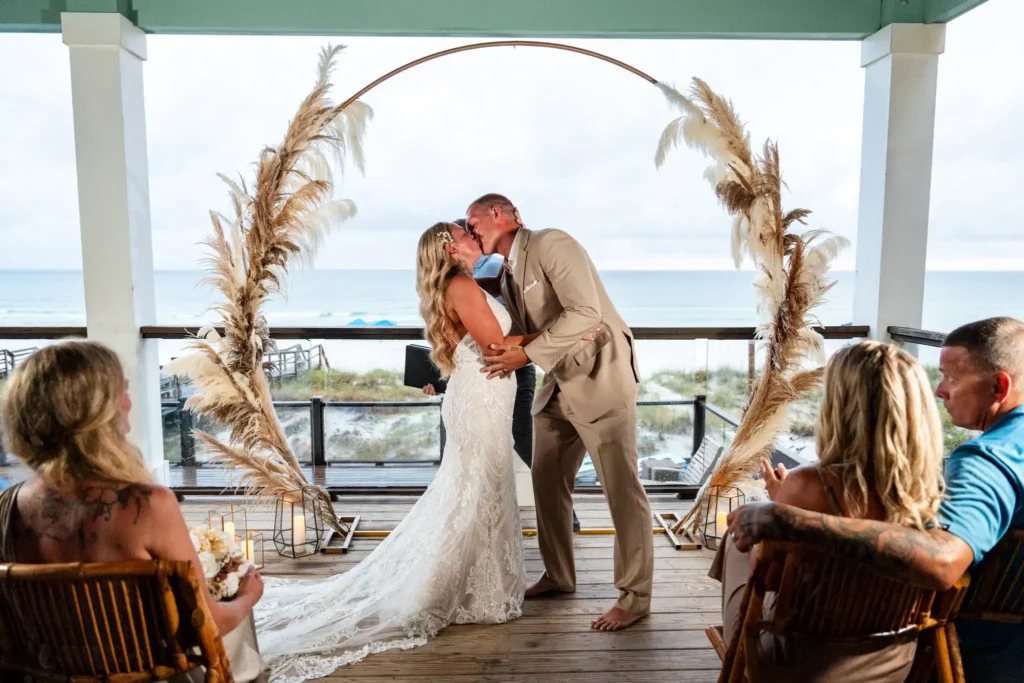 a man and woman kissing under an arch first kiss after getting married in destin fl | KDH Weddings