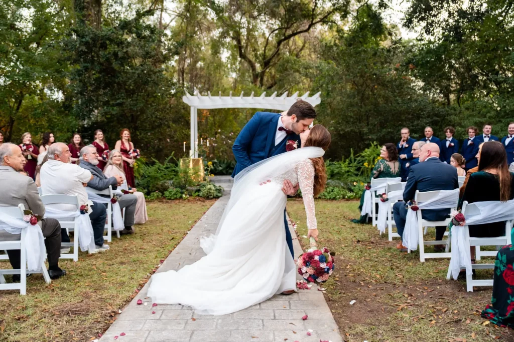 husband kissing wife at the alter outside bride leaning back being held by grooms arm