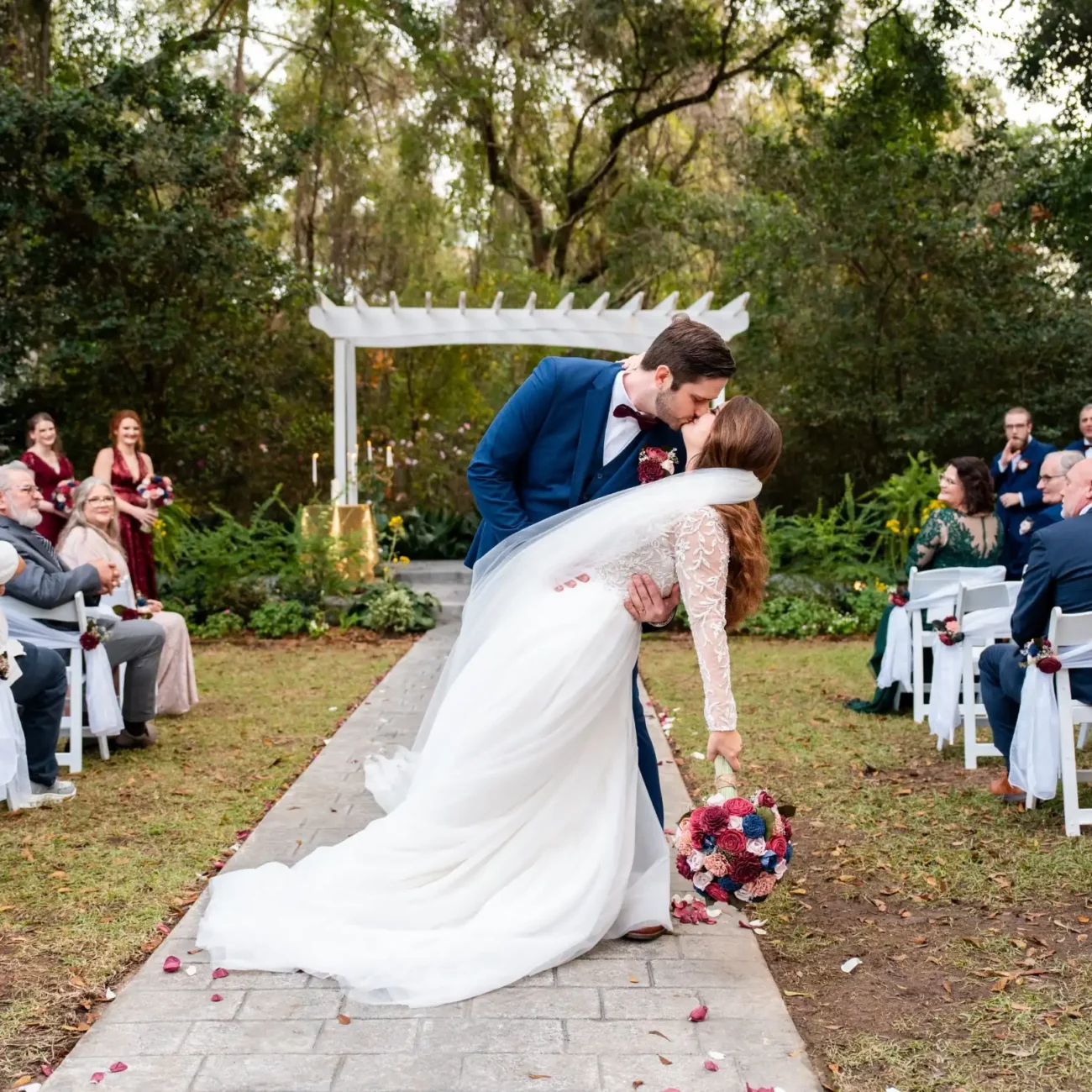 husband kissing wife at the alter outside bride leaning back being held by grooms arm