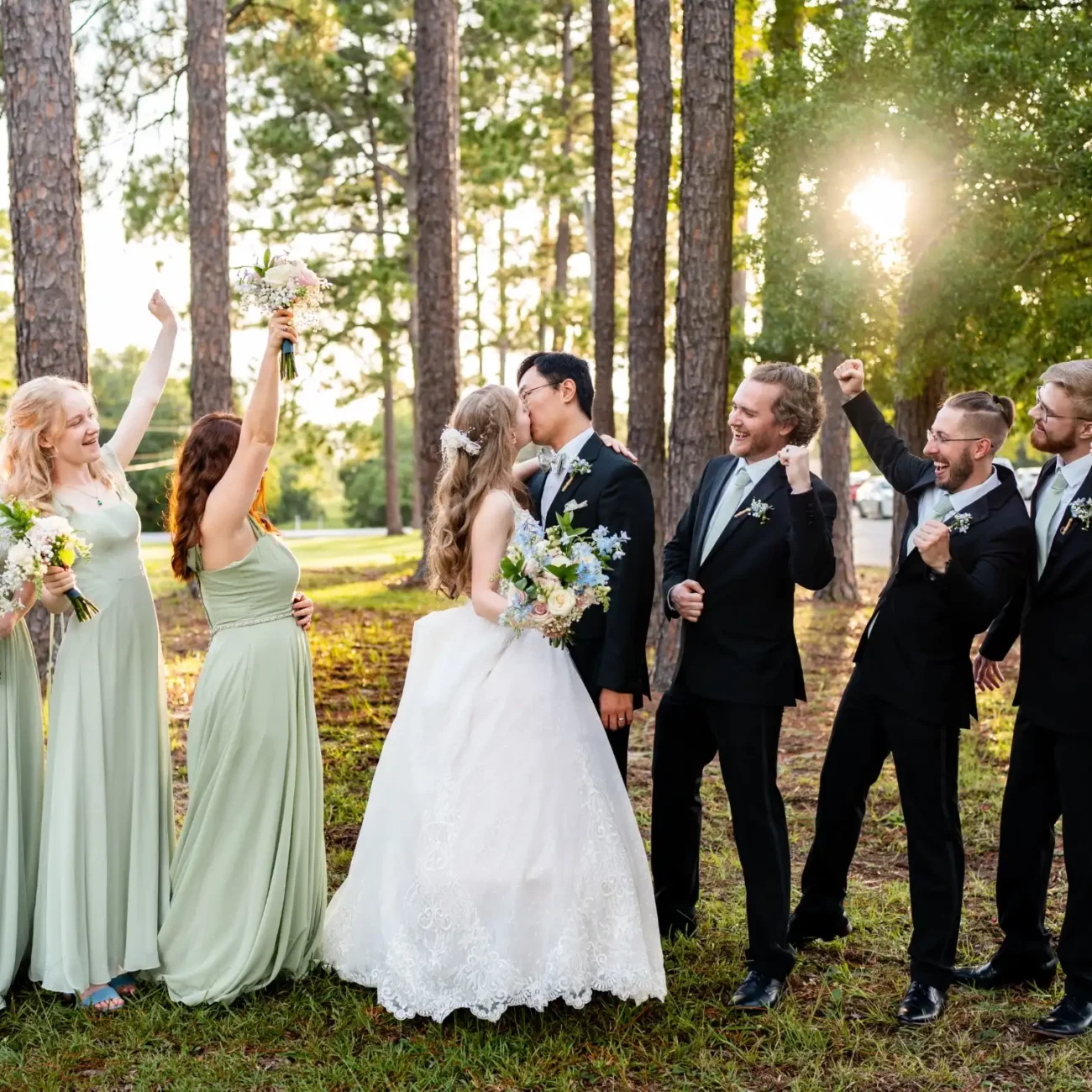 husband and wife kissing with groomsmen and bridesmaids on each side in a forst