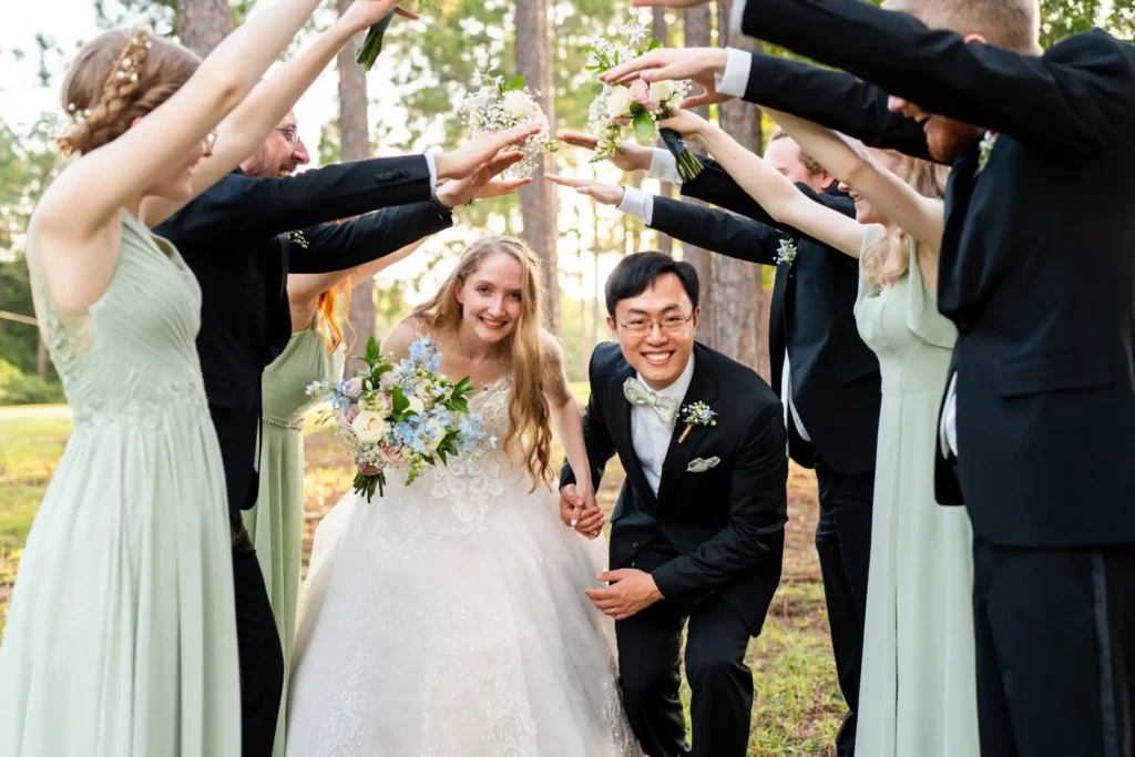 husband and wife walking under arch of groomsmen and bridesmaids hands