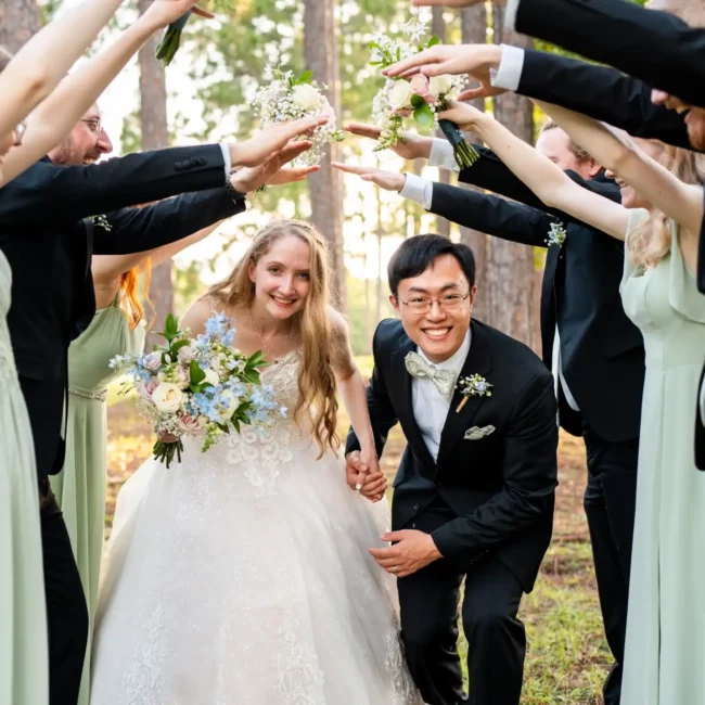 husband and wife walking under arch of groomsmen and bridesmaids hands