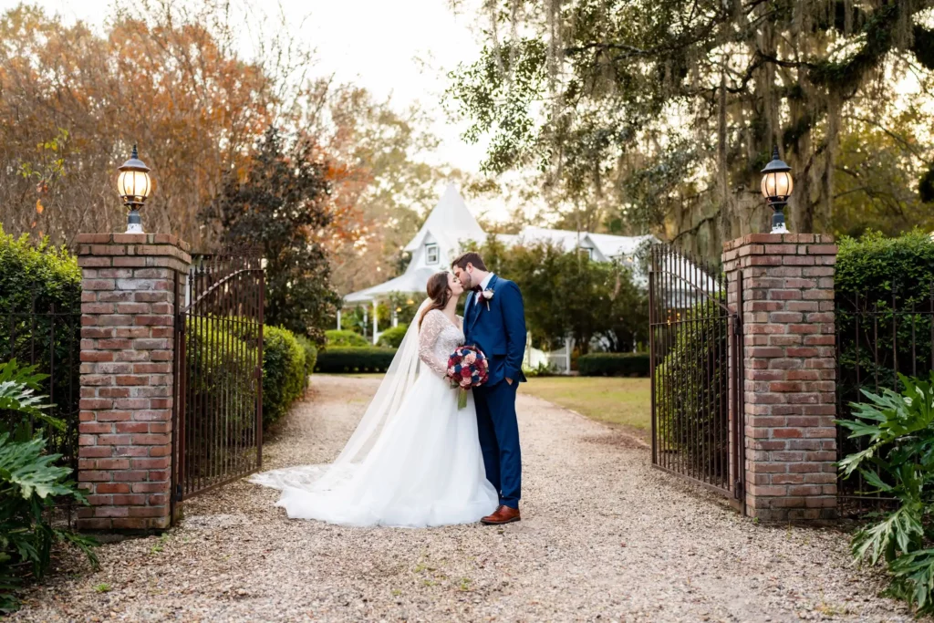 husband and wife rustic blue suit white veil gravel path between stone gateways