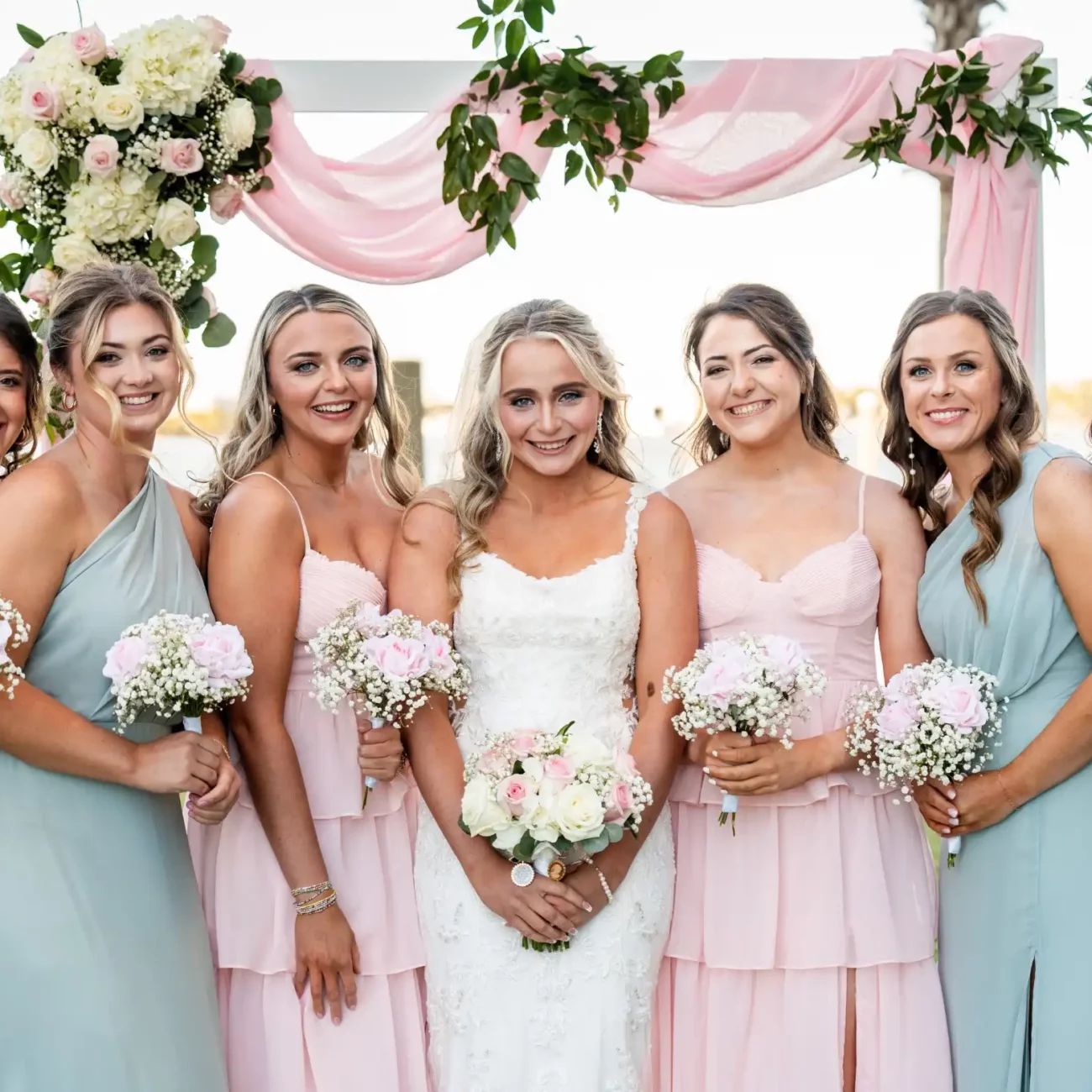 bridge and bridesmaids holding white flowers pink dresses and green dresses