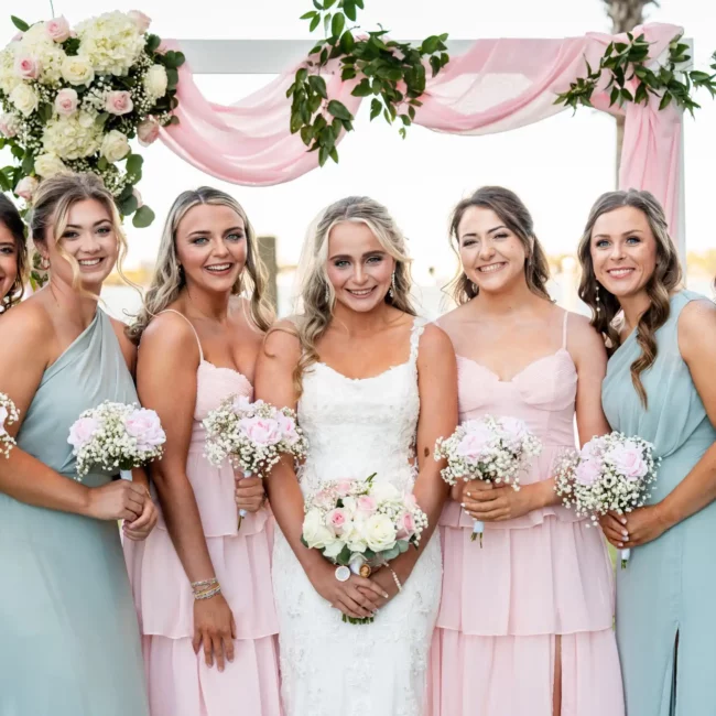 bridge and bridesmaids holding white flowers pink dresses and green dresses
