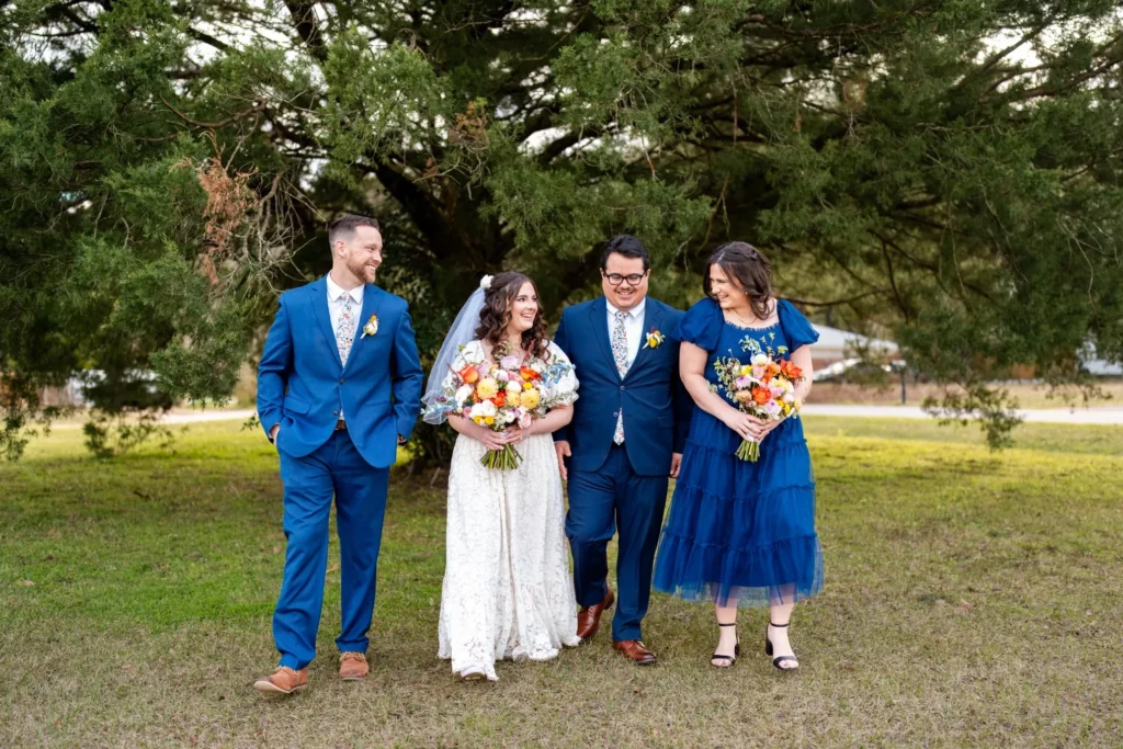 The Wedding Photo Shot List (Free Printable Checklist) 5 Charles and Julia walking across the lawn with their two attendants, the groomsmen in cobalt blue suits and bright spring bouquets