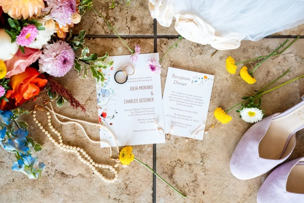 The Wedding Photo Shot List (Free Printable Checklist) 1 wedding invitations and wedding ring on tile floor with flowers around them and necklaces