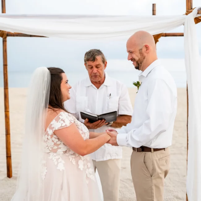 Chad & Rena holding hands about to get married under a canopy on Orange Beach