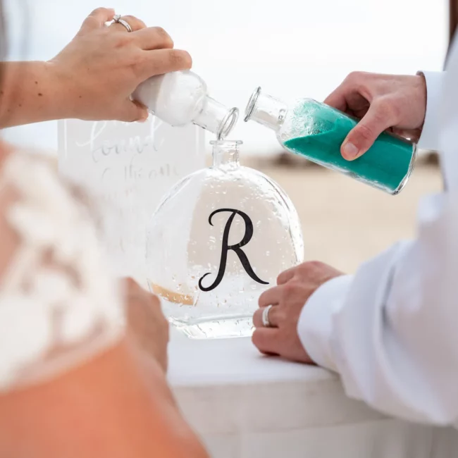 Chad & Rena adding colored sand to a glass bottle with the letter R on it to symbolize their new marriage