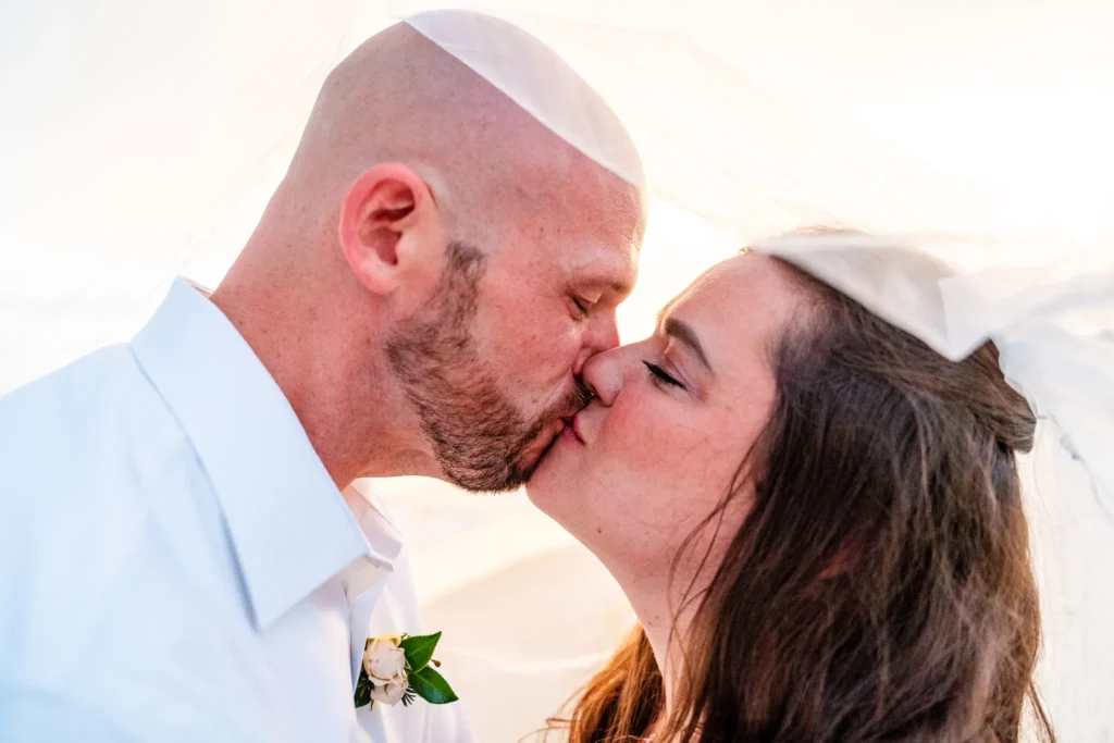 Panama City Beach Wedding Photographer 4 Chad & Rena kissing under Rena's veil on Orange Beach after getting married