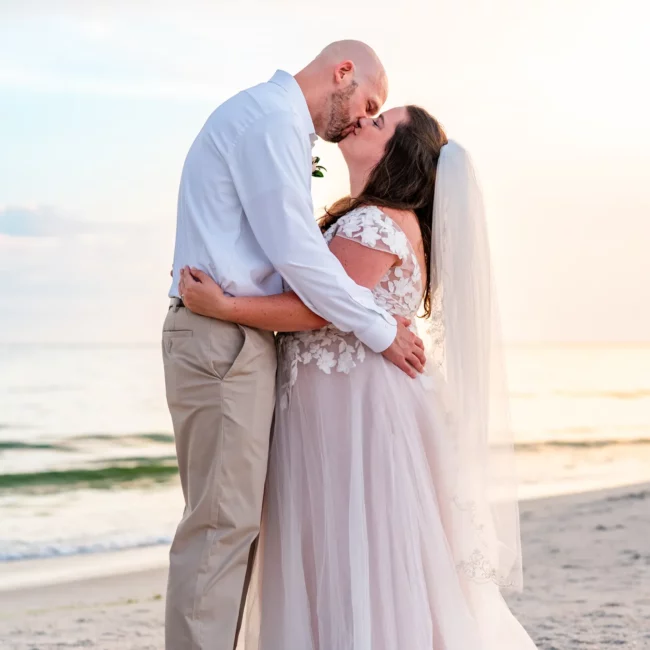 Chad & Rena kissing while standing on the beach after getting married on Orange Beach