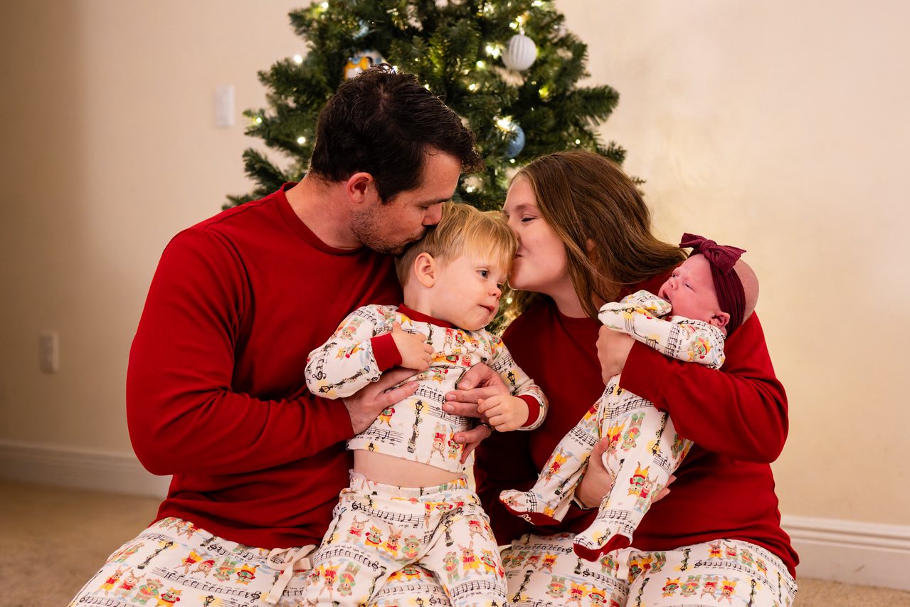 korbin henderson of kdh weddings with his wife and two baby boys during a Christmas photo shoot with a Christmas tree in the background