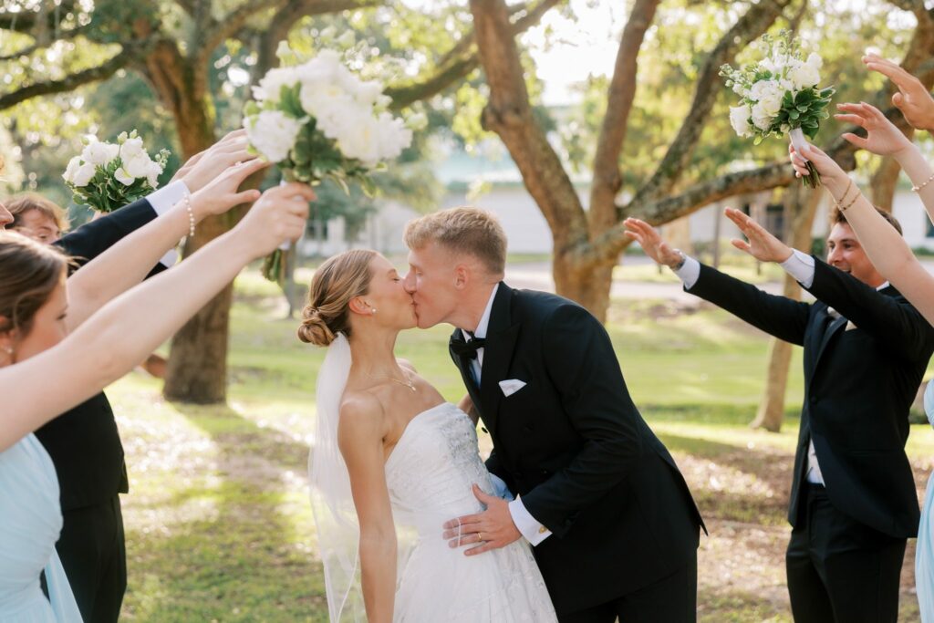 Jake & Lauren's Hurlburt Field Wedding on Santa Rosa Sound 3 Jake and Lauren kiss under an arch of bouquets and raised arms from their wedding party