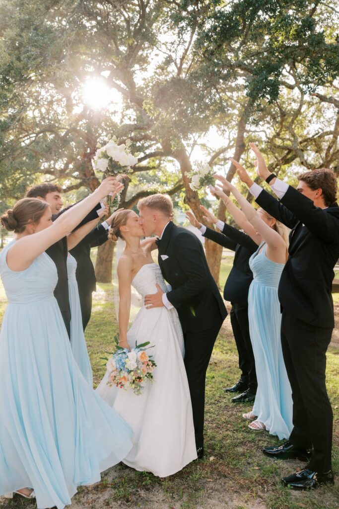 Jake & Lauren's Hurlburt Field Wedding on Santa Rosa Sound 4 Bridal party raising bouquets over the couple beneath a live oak