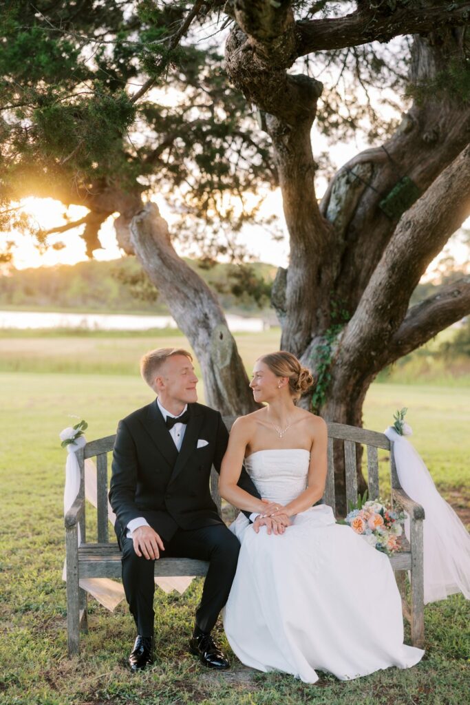 Jake & Lauren's Hurlburt Field Wedding on Santa Rosa Sound 5 Bride and groom sit on a wooden bench under a live oak on Hurlburt Field