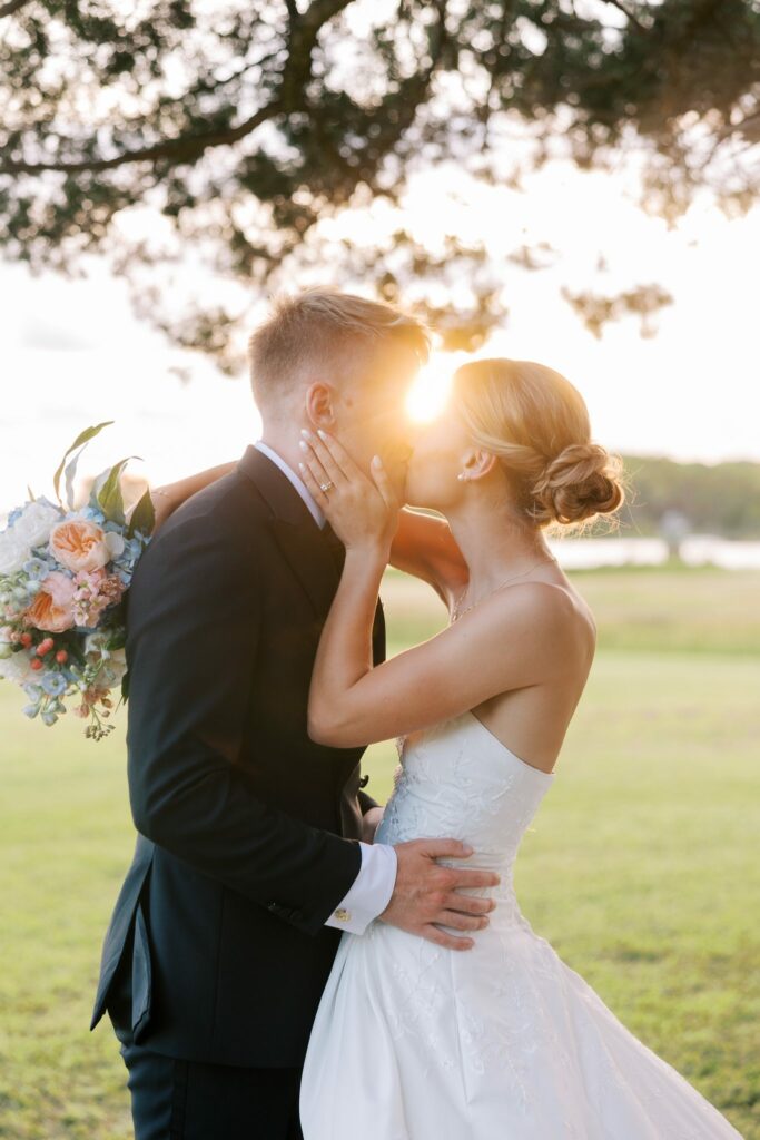 Jake & Lauren's Hurlburt Field Wedding on Santa Rosa Sound 6 Jake and Lauren kiss with the evening sun flaring between them beside Santa Rosa Sound