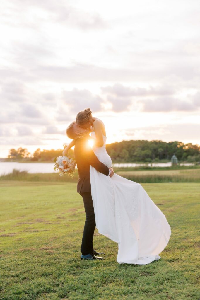 Jake & Lauren's Hurlburt Field Wedding on Santa Rosa Sound 7 Jake lifts Lauren on the grass along Santa Rosa Sound at sunset