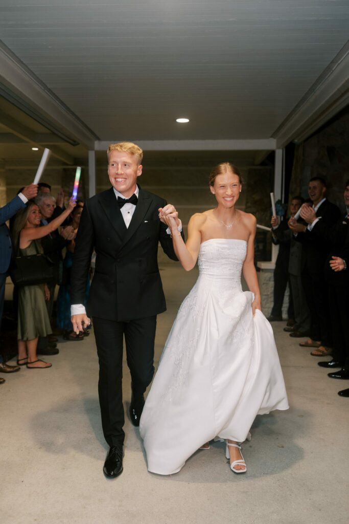 Jake & Lauren's Hurlburt Field Wedding on Santa Rosa Sound 12 Guests with glow sticks line the covered entrance for Jake and Lauren's exit