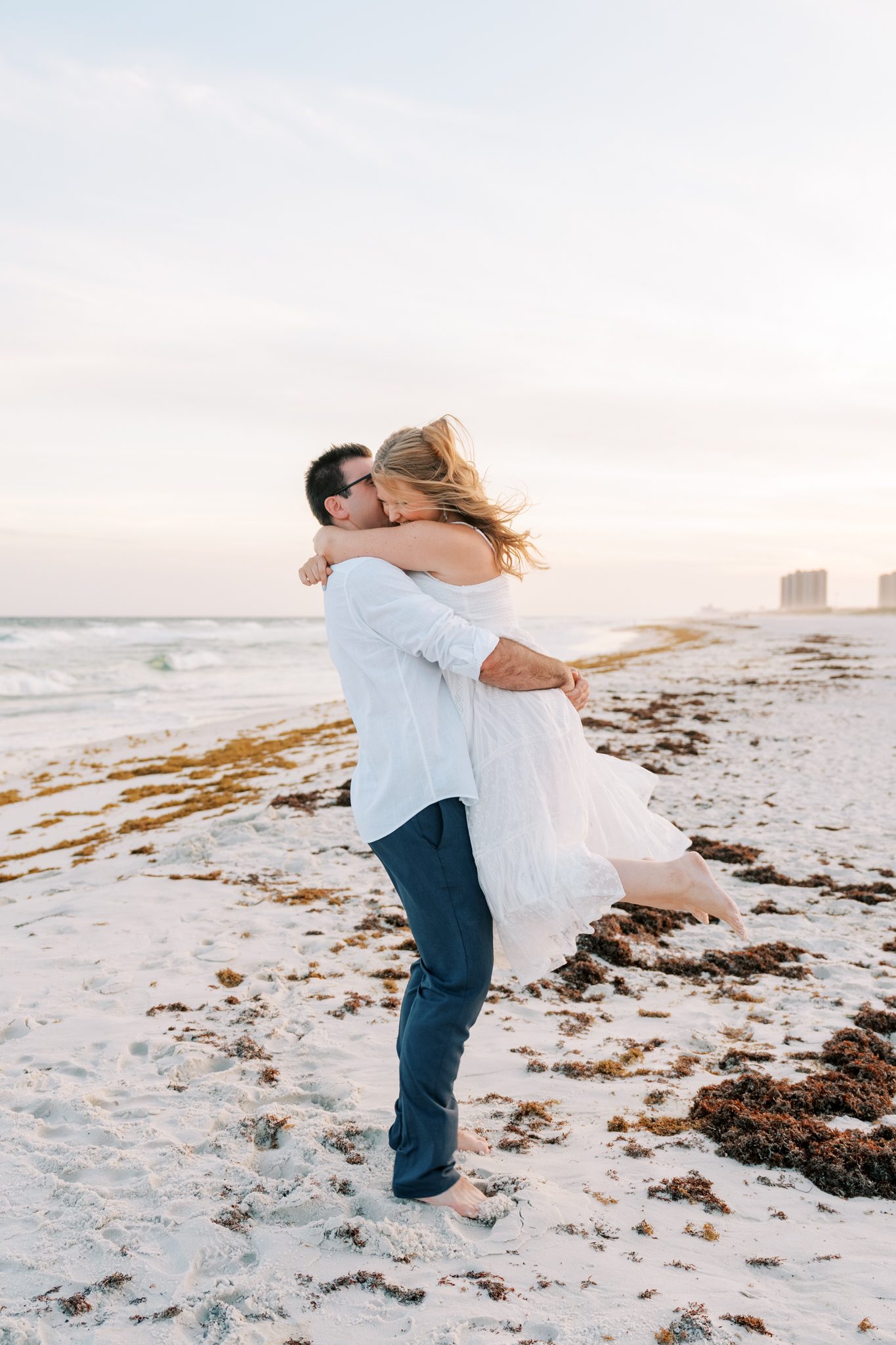 Andrew lifts Katie into a hug at the water's edge during their Pensacola Beach engagement session