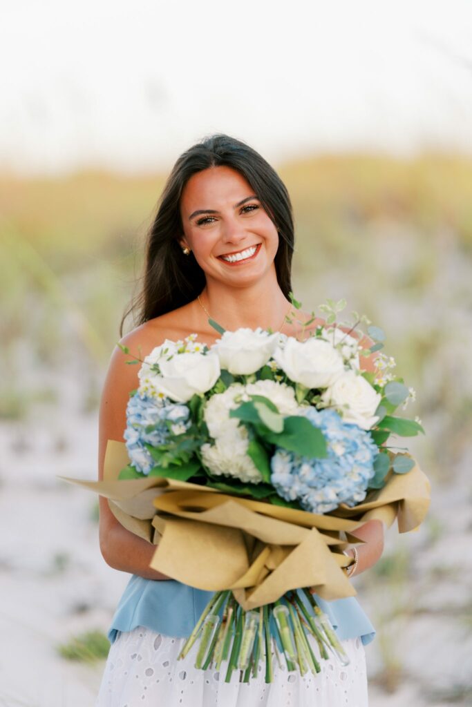 Hayes & Mallory's Surprise Proposal on Pensacola Beach 7 Mallory holding a bouquet of white roses and blue hydrangeas from Anna Marie's