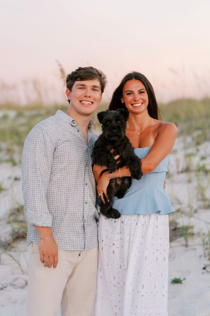 Hayes & Mallory's Surprise Proposal on Pensacola Beach 14 Hayes and Mallory holding a small black dog after the proposal