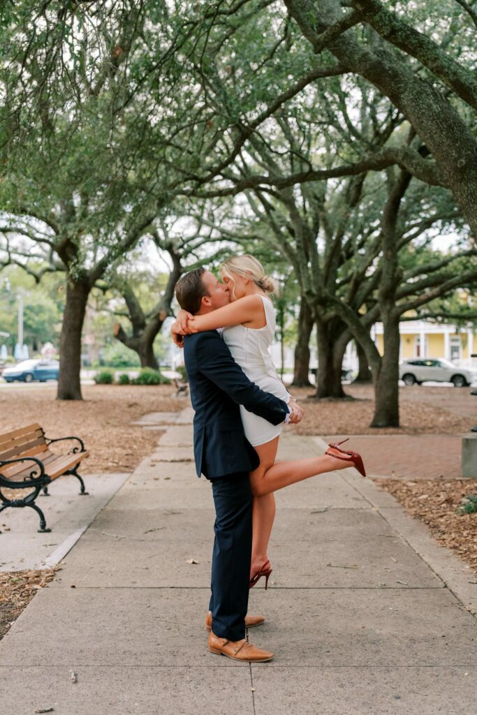 Engaged couple embrace on a brick path beneath the live oaks in Seville Square, Pensacola