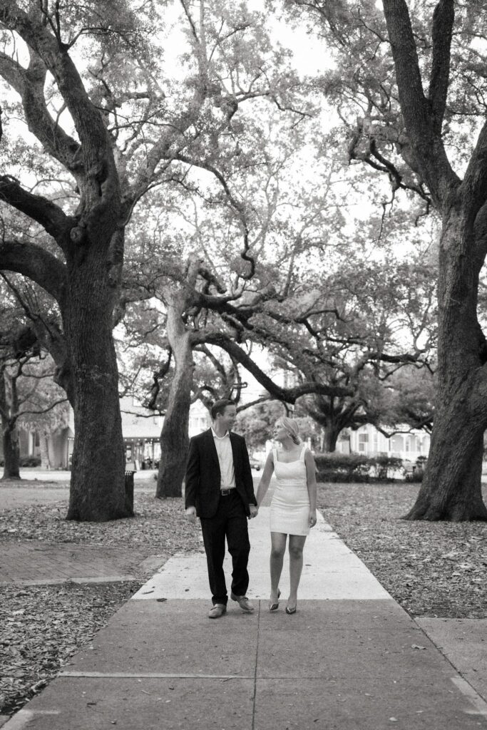 Black and white photo of the couple walking beneath the oak canopy of Seville Square