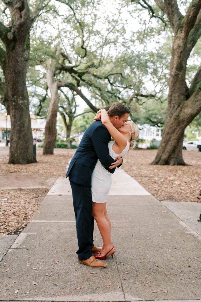 Sean and Brooklin kiss on a path between the live oaks