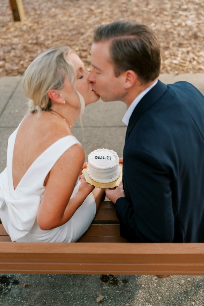Couple on a Seville Square bench sharing a kiss over a little cake