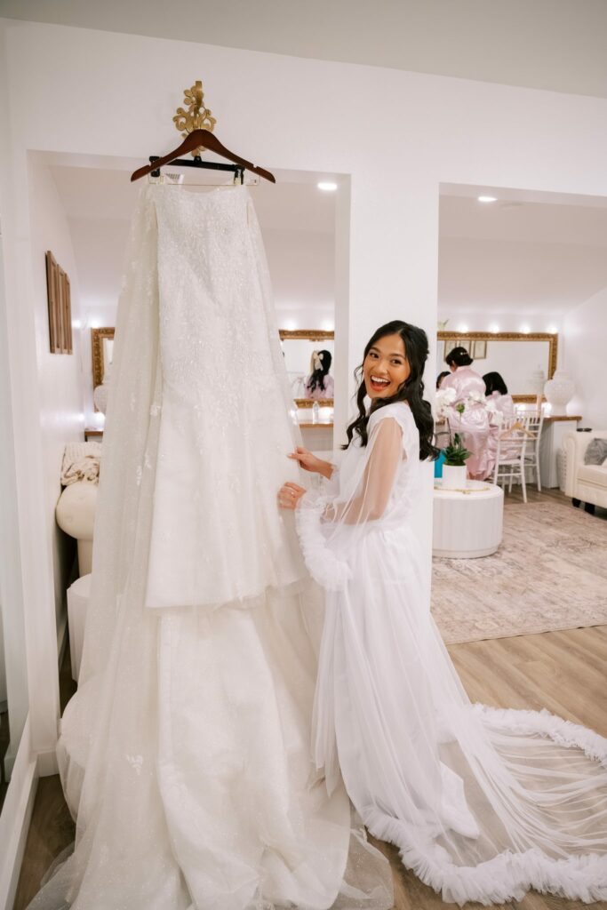 Bret & Ella's Spring Warehouse Wedding in Pensacola 2 Ella beside her wedding gown hanging in the Supposey bridal suite