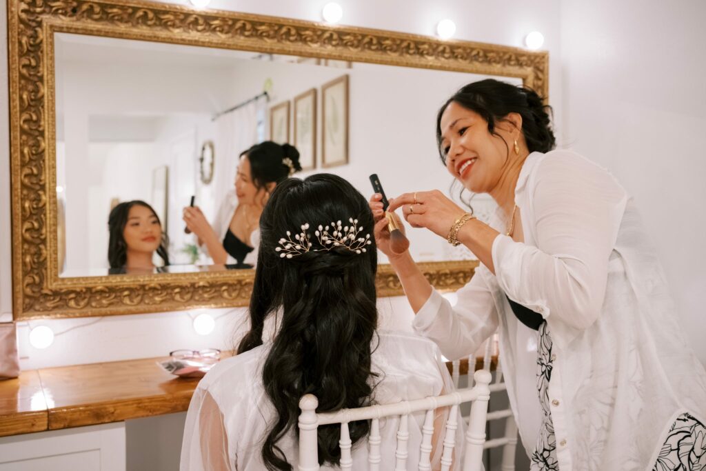 Bret & Ella's Spring Warehouse Wedding in Pensacola 3 Final touches on the bride's hair at the gold-framed mirror in the bridal suite