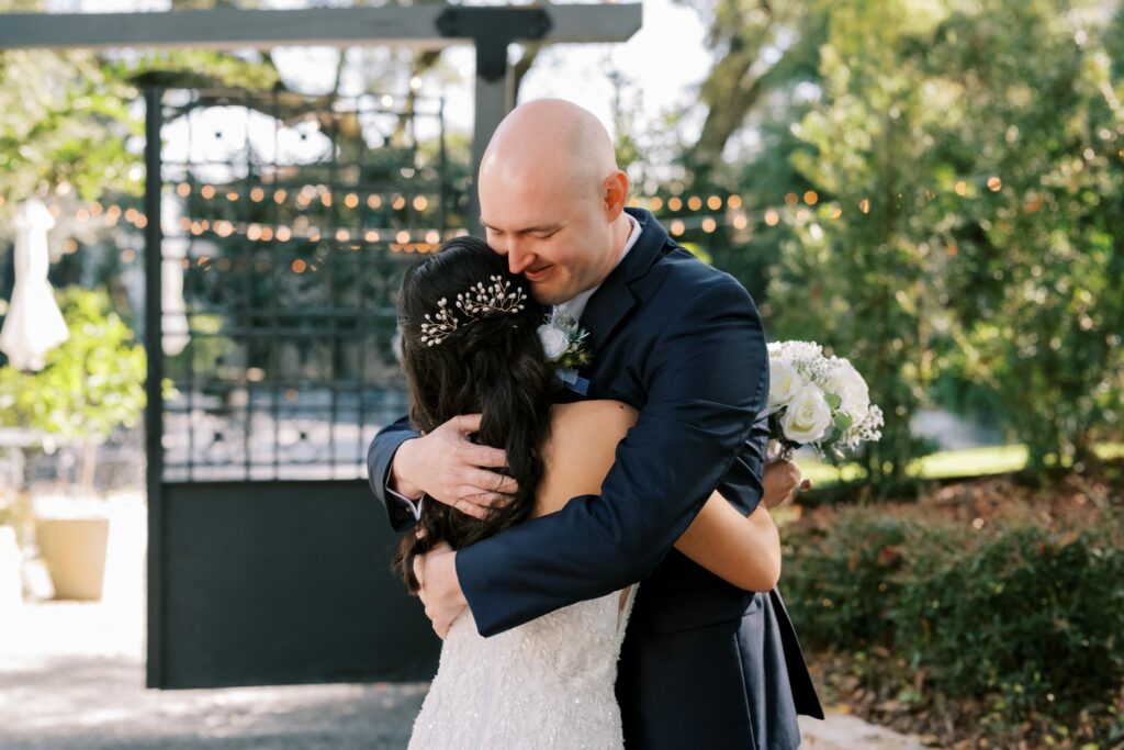Bret & Ella's Spring Warehouse Wedding in Pensacola 5 Groom hugs his bride by the iron garden gate after their ceremony at Supposey in Pensacola