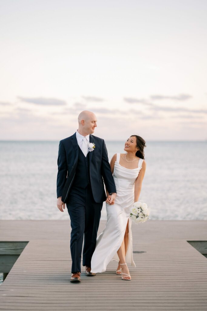 Bret & Ella's Spring Warehouse Wedding in Pensacola 6 Bret and Ella walk along a wooden dock over the bay at sunset