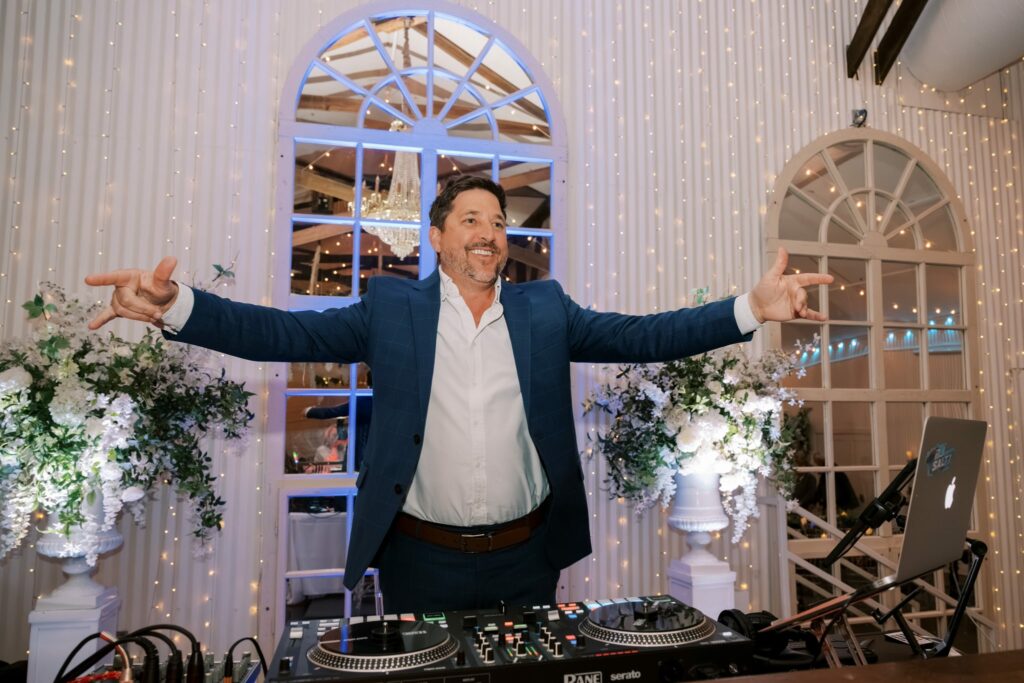 Bret & Ella's Spring Warehouse Wedding in Pensacola 11 DJ Salty with arms outstretched at the DJ booth during the reception