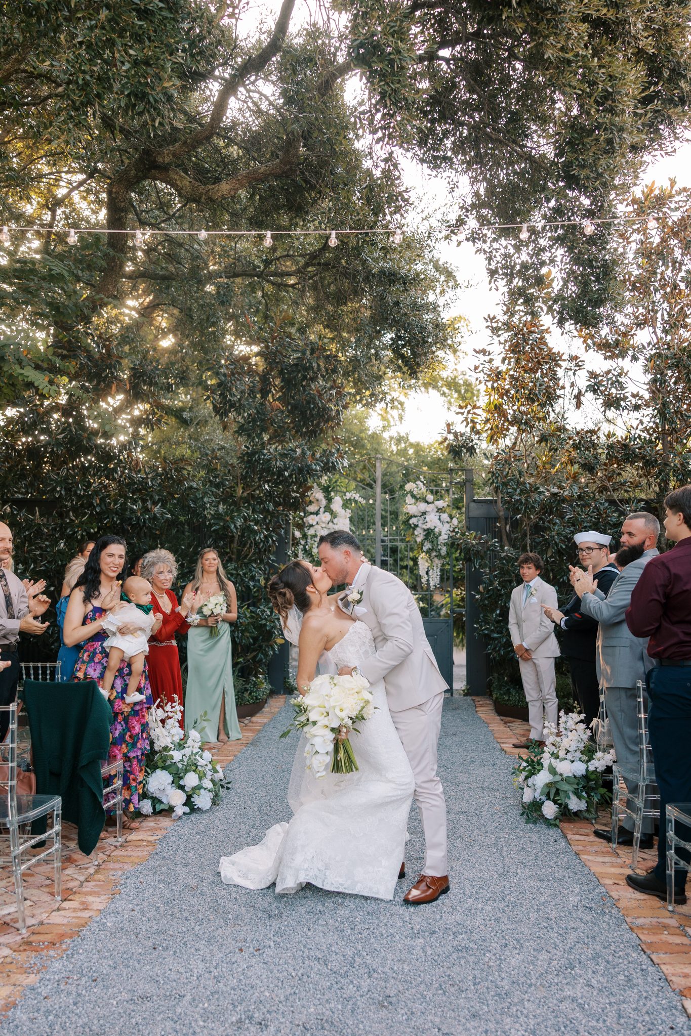 Nick and Amanda kiss at the end of the garden ceremony aisle at Supposey Warehouse and Gardens in Pensacola