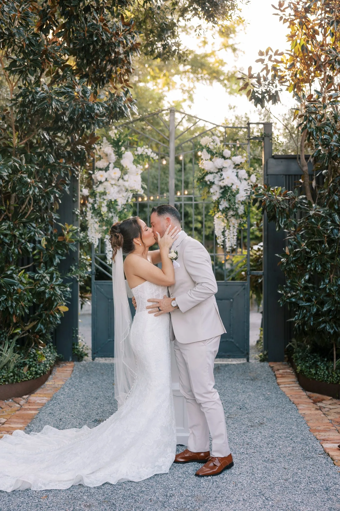Pensacola Wedding Photographer - KDH Weddings 8 Nick and Amanda kiss in front of the black iron gate at the end of the Supposey garden aisle