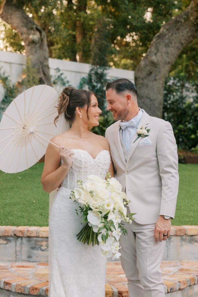 Nick & Amanda's Supposey Warehouse Wedding in Pensacola 8 Nick and Amanda share a laugh on the lawn with a white parasol at Supposey