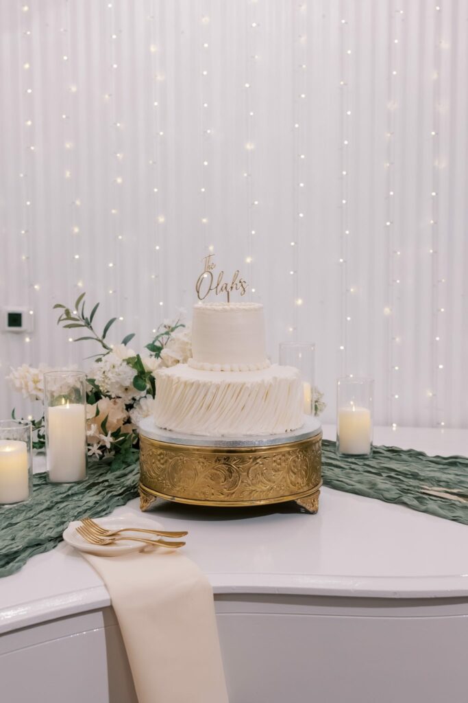 Nick & Amanda's Supposey Warehouse Wedding in Pensacola 12 White tiered wedding cake on a gold stand at the Supposey reception