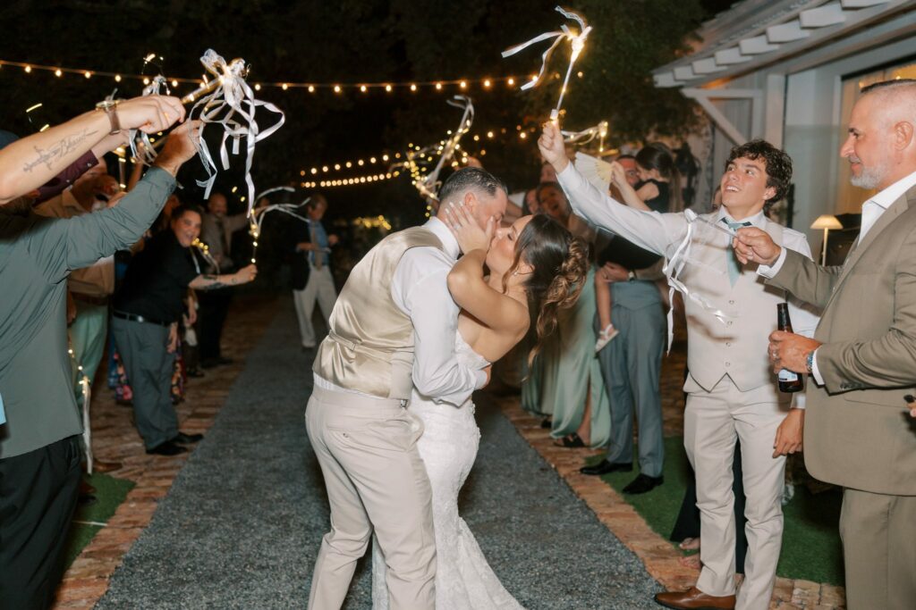 Nick & Amanda's Supposey Warehouse Wedding in Pensacola 16 Nick and Amanda kiss during their send-off down the garden aisle under string lights
