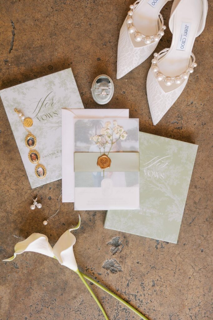 Nick & Amanda's Supposey Warehouse Wedding in Pensacola 17 Wedding invitation suite, pearl heels and rings styled in a flat lay at Supposey Warehouse