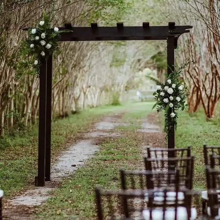 Josh & Haley's Hidden Oak Farm Wedding in Milton, FL 4 Wooden ceremony arch with white flowers on the Tree Lined Drive at Hidden Oak Farm