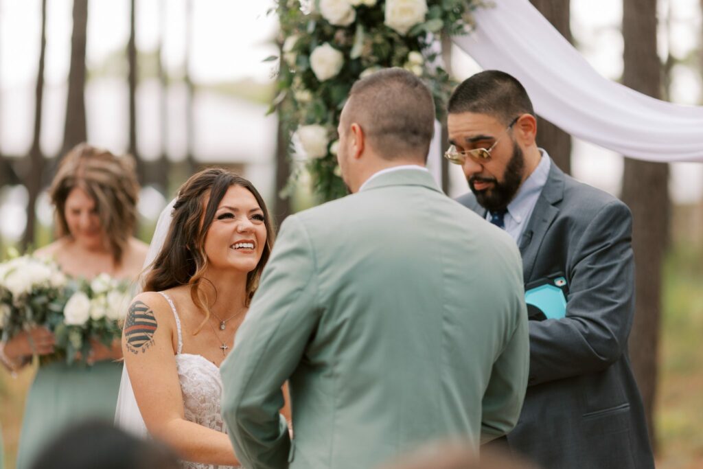 Josh & Haley's Hidden Oak Farm Wedding in Milton, FL 9 Haley smiles at Josh during the vows under the floral arch at Hidden Oak Farm in Milton, FL