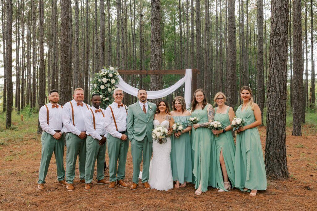 Josh & Haley's Hidden Oak Farm Wedding in Milton, FL 12 Josh and Haley with their sage green wedding party lined up in front of the pines at Hidden Oak Farm