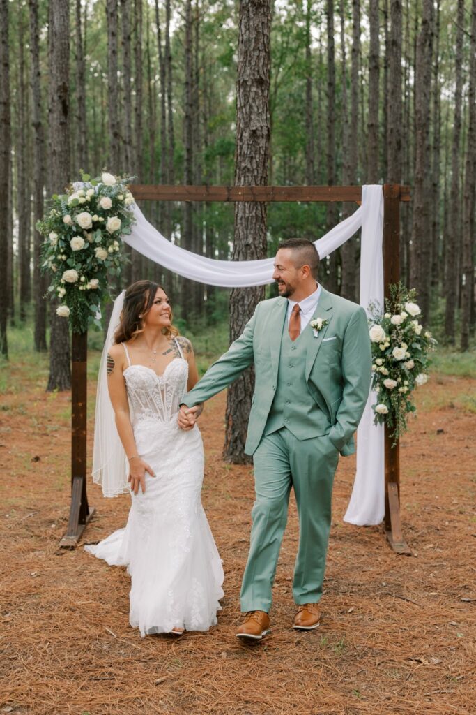 Josh & Haley's Hidden Oak Farm Wedding in Milton, FL 15 Josh and Haley walk together from the pine ceremony arch at Hidden Oak Farm in Milton, FL